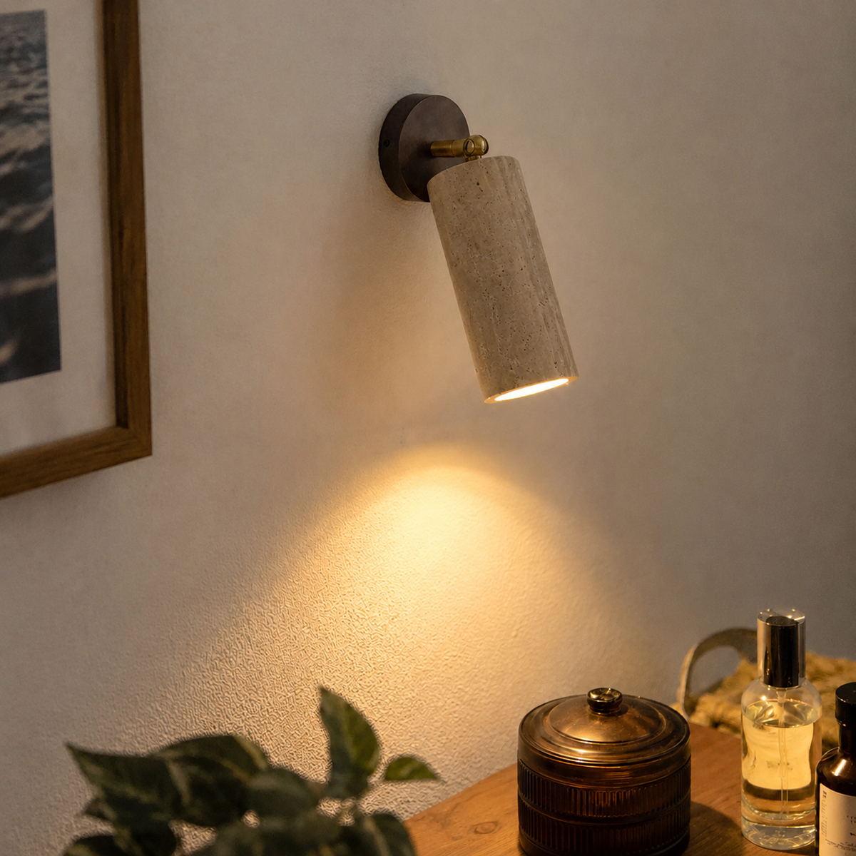 Applique murale orientable en travertin naturel avec fixation murale en métal et détails dorés, diffusant une lumière chaude vers le bas. Image